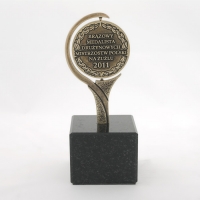 statuetka wykonana w formie medalu; odlew metalowy wykończony w kolorze mosiądzu patynowanego; podstawa czarny granit