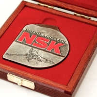 medal odlewany w pudełku drewnianym z wkładką kształtową; wykończenie medalu w kolorze patynowanego srebra; malowany ręcznie