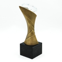 statuetka odlana z materiałów kompozytowych; wykończenie w kolorze patynowanego mosiądzu; szklany 'diament'; podstawa czarny granit; wysokość statuetki  ok. 27 cm